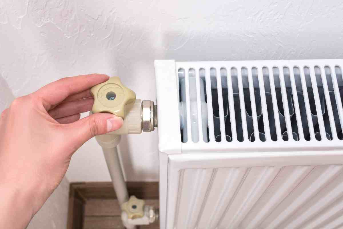 una mano gira una manopola dei termosifoni per farli sfiatare