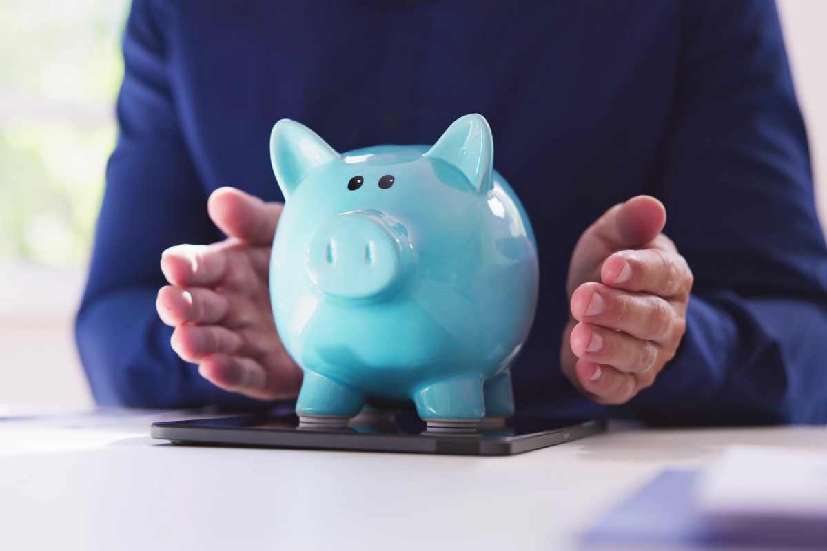 una persona stringe tra le mani un salvadanaio a forma di porcellino