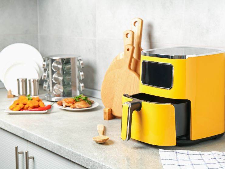 friggitrice ad aria di colore giallo sistemata su un piano in cucina