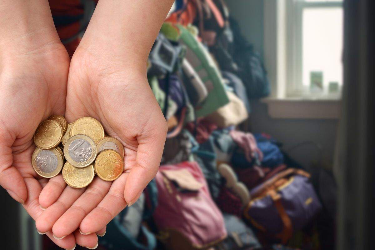 borse in disordine nell'armadio e mano che tiene spiccioli