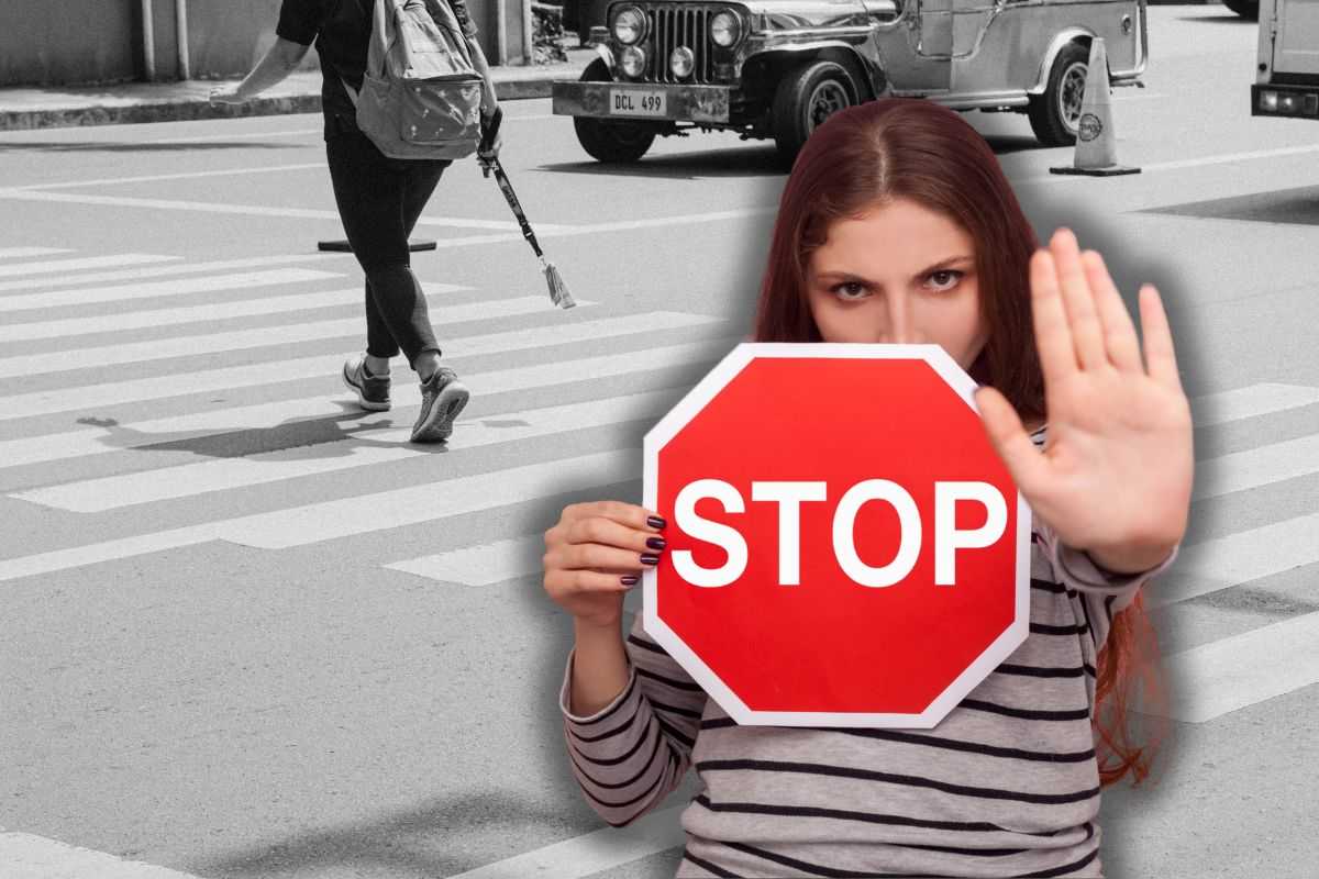 donna che attraversa su strisce pedonali e un'altra con in mano cartello con la scritta stop