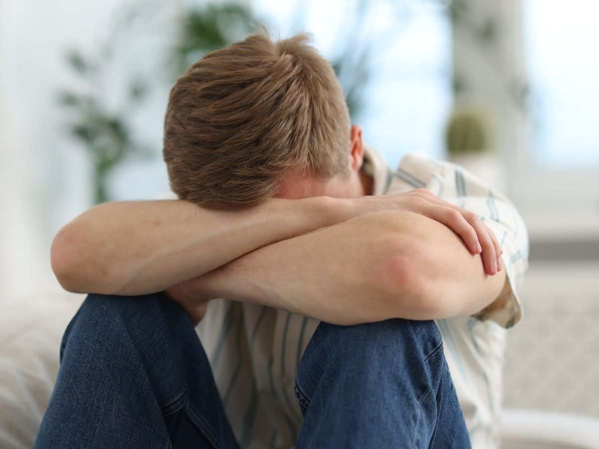 persona triste con testa sulle gambe