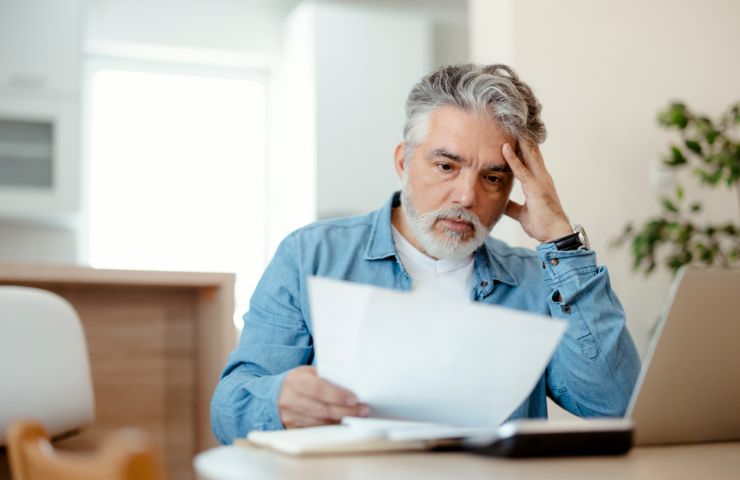 uomo disperato con bollette in mano